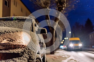 Parked car with light on covered by snow at night