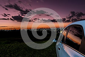 Parked car in sunset time with lights of the city backround