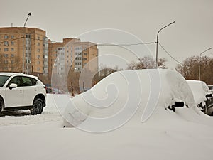 Parked cars buried under white snow on the street