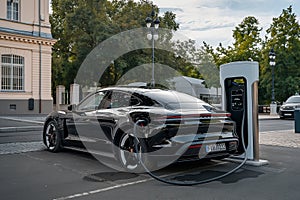 A parked electric car is being recharged at an electric charging station.
