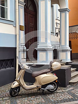 Parked electric scooter on paving stones. Entrance to the building. Modern architecture.