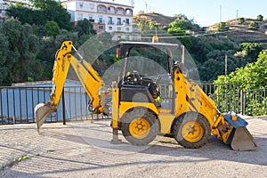 Parked mini wheeled yellow excavator.