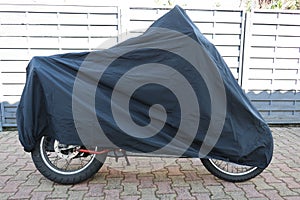 Parked motorbike with protective cover in the street