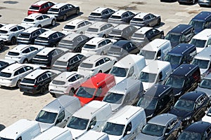 Parked new cars from different producers and colors recently discharged from cargo ships.