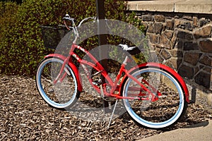 A Parked red colored ladies bicycle.