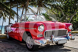 Parked red vintage car in Havana Cuba near the beach