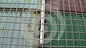 Parked shipping containers stacked beside a fence