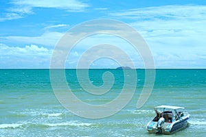 Parked speed boat on blue ocean with blue sky and fluffy clouds