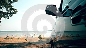 Parked van reflects sunbathing and swimming people on the beach. Summer vacations travel time