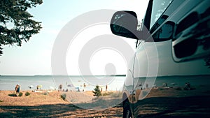 Parked van reflects sunbathing and swimming people on the beach. Summer vacations travel time