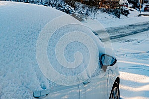 Parked white car covered by a thick layer of snow, covering top