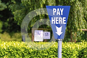 Parking charge pay here blue sign post in green environment