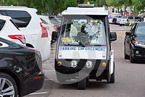 Parking Enforcement vehicle by parked cars to check parking mete
