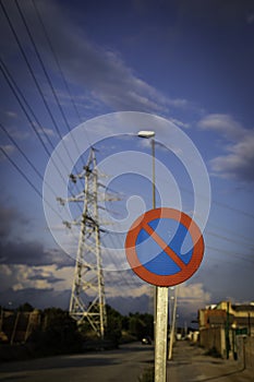 Parking forbidden sign from Spain on a cloudy day with high voltage tower in the background