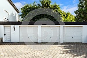 Parking garage in residential house for cars with white block doors in sunny day