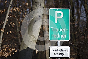 A parking lot sign at the forest in German with the words: bereavement speaker and a white sign with the words: bereavement counse photo