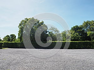 Parking lot sprinkled with gravel bush green tree blue sky nature background