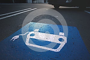 parking lot with symbol of a car with cable plug painted on asphalt in blue and white.