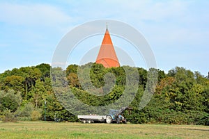 Parking lot with a tractor near Kirchdorf, Insel Poel, Germany with church roof behind the trees