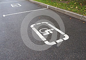 Parking lot with white painted sign of wheelchair on asphalt, parking spaces for disabled visitors
