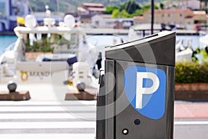 Parking meter sign blue white p car parked in city street of harbor town