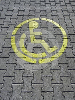 Parking place for disabled, yellow sign on grey brick