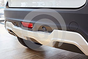 Parking sensors on a white car, rear bumper with reflector and exhaust pipe and place to install the hook for towing
