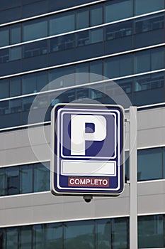 Parking signpost with completo text and modern building background photo