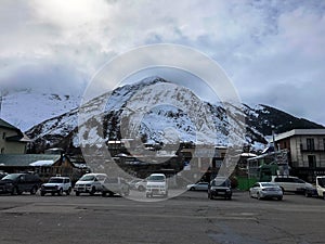 Parking and stone houses, buildings, shops, refueling on a beautiful mountain winter resort with high mountain peaks and rocks