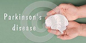 Parkinson`s disease is standing on a paper, hands holding brain, dementia diagnosis, Alzheimer