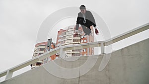 Parkour in a business suit. The guy is a businessman jumping at the top. Tracer office worker. Slow motion.