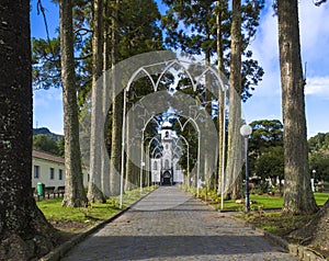 Parkway with small white and gray church of Sao Nicolau at the village of Sete Cidades on the island of Sao Miguel