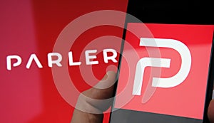 Parler app logo seen on the screen of smartphone and on the blurred background. Parler is a new social media platform promoting