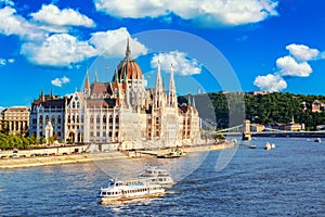Parliament and riverside in Budapest Hungary with sightseeing ships during summer sunny day with blue sky and clouds. Travel and