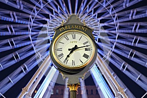 Parliament street clock at night with Christmas ferris wheel in the back. 1459 is engraved on the clock face.