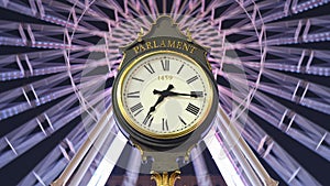 Parliament street clock at night with Christmas ferris wheel in the back timelapse. 1459 is engraved on the clock face.