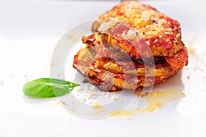 Parmigiana di melanzane. Traditional Italian dish: Baked eggplants with Parmesan cheese, decorated with fresh basil. photo