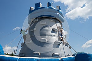 Boy and girl climbing on rope at high inflatable tower