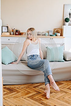 Parquet in the kitchen. A girl in jeans and a T-shirt is sitting on the couch