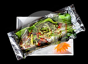 Parrot fish grilled in Vietnamese style with vegetables isolated on black background top view