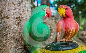 Parrots red and green statue in garden.