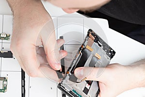 Parsing a mobile phone. A specialist repairs a smartphone in a service center