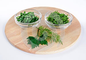 Parsley and dill leaves in two little glass bowls and lone twigs