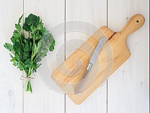 Parsley, kitchen knife and wooden cutting board