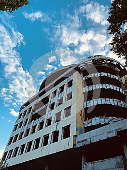 Part of an abandoned building against a background of blue sky and white clouds