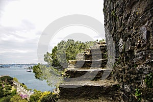 Part of an abrupt ladder of fortress of Rumeli Hisari aspiring into sky. At a background Bosphorus and Bosphorus Bridge.