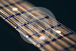 Part of an acoustic guitar, guitar fretboard on a black background.