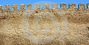 A part of an ancient fortress wall, castle wall with a tooth shaped parapet made from limestone bricks, coquina rocks, yellow