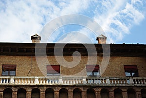 Part of an ancient stately building with two chimneys that stand out against the sky.