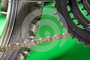 part of bicycle chain, tire and chainset teeth.  green background.